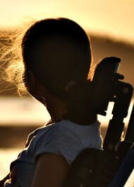 Silhouette of young girl aiming rifle at sunset, hair blowing in wind, for personal injury attorney website