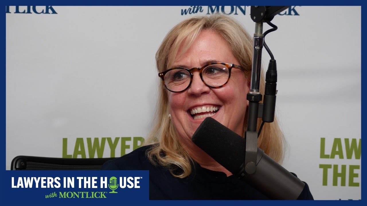 Smiling blonde woman with glasses speaking into microphone, with "Lawyers in the House" text overlay. SEO-friendly alt text for injury attorney website.